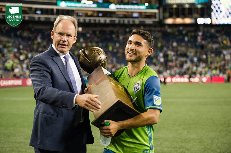 With coach Brian Schmetzer at his side, Cristian Roldan carries off the spoils of a 3-0 win over San Jose – the Heritage Cup – after scoring goals two minutes apart. (Courtesy Jane Gershovich / Sounders FC)