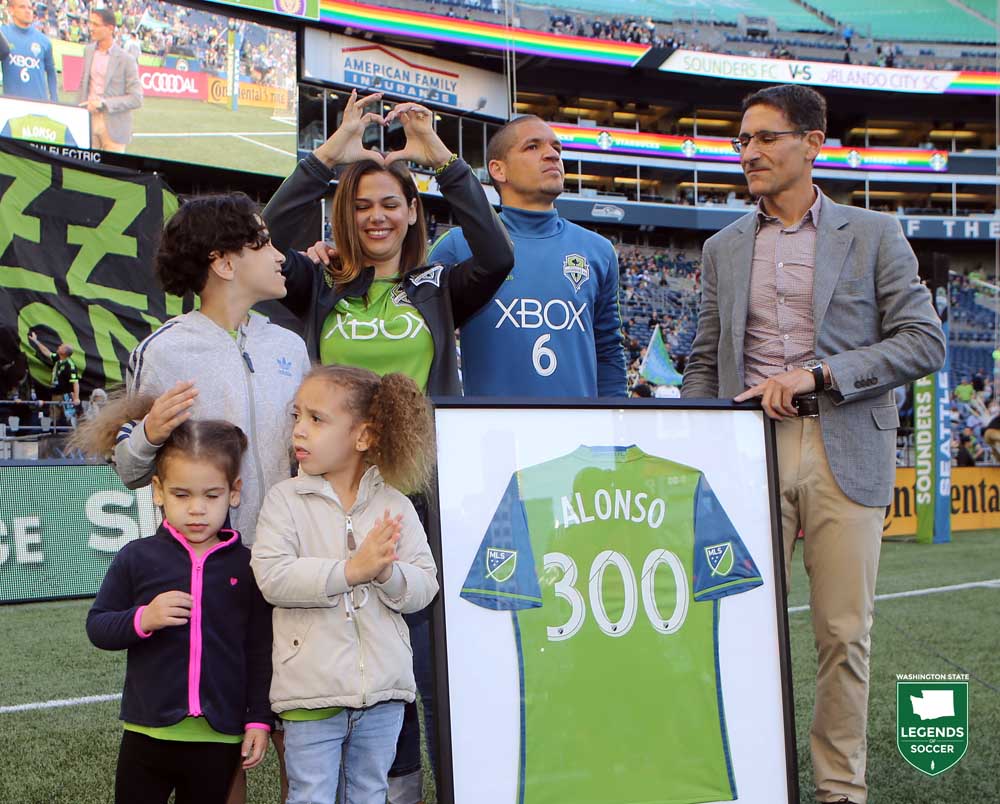 Sounders owner Adrian Hanauer presents Osvaldo Alonso with a framed jersey to commemorate his record 300th appearance for the club. (Courtesy Corky Trewin / Sounders FC)