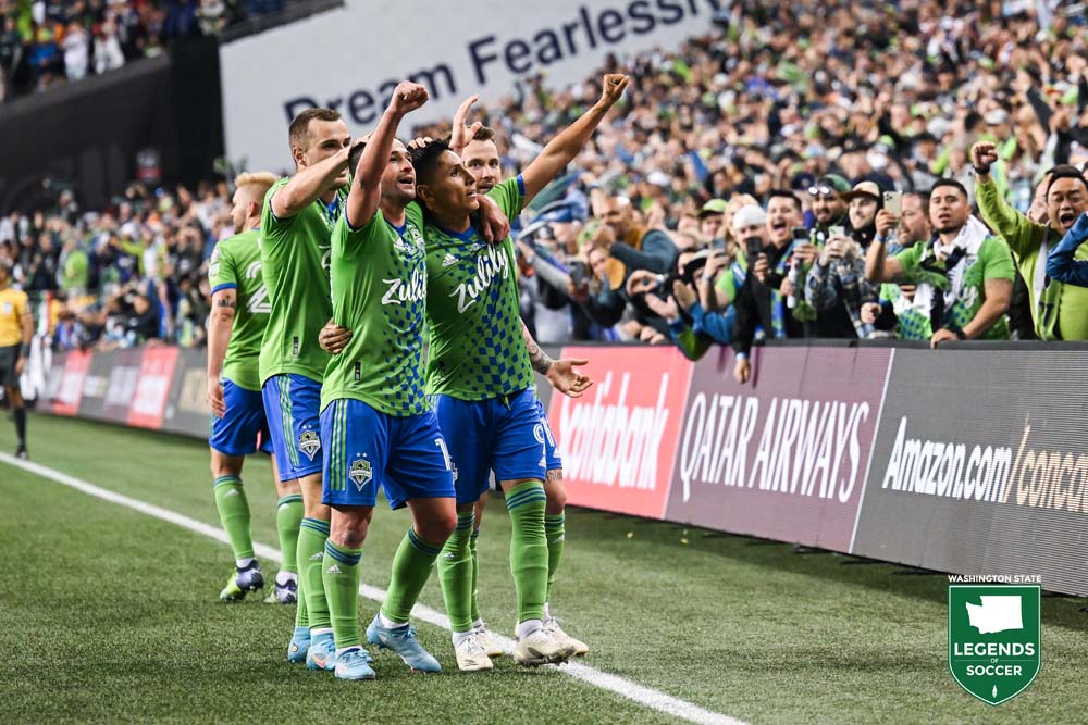 Nicolas Lodeiro (l) and Raul Ruidiaz salute the Sounders fans after the latter scores his second goal vs. Pumas in the Concacaf Champions League second leg final. (Courtesy Rod Mar/Sounders FC)